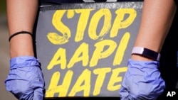 FILE - A woman holds a sign and attends a rally to support stop AAPI (Asian Americans and Pacific Islanders) hate at the Logan Square Monument in Chicago, March 20, 2021.