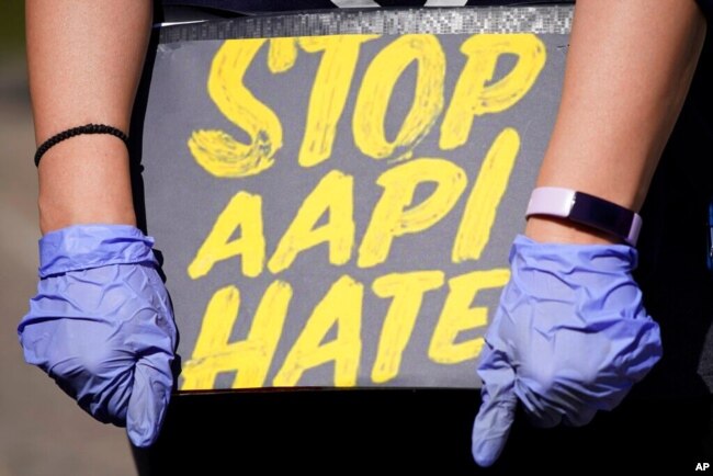 FILE - A woman holds a sign and attends a rally to support stop AAPI (Asian Americans and Pacific Islanders) hate at the Logan Square Monument in Chicago, March 20, 2021.