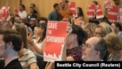 Supporters of music venue The Showbox wave signs at a Seattle City Council meeting, Aug. 6, 2018.