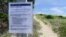 FILE - A sign warns visitors about the possible presence of sharks along the Cape Hatteras National Seashore in Cape Hatteras, North Carolina, July 7, 2015.