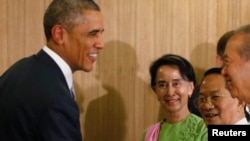 Myanmar opposition leader Aung San Suu Kyi (C) looks on as U.S. President Barack Obama shakes hands after a roundtable with members of parliament and civil society to discuss Myanmar's reform process, in Naypyitaw November 13, 2014. Obama is in Myanmar to