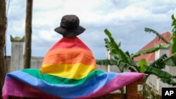 FILE - A gay Ugandan man covers himself with a pride flag as he poses for a photograph in Uganda Saturday, March 25, 2023.