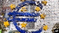 FILE - The Euro sculpture in front of the old European Central Bank building is photographed behind rain drops on a window in Frankfurt, Germany, Oct. 18, 2016.