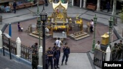 FILE - Thai police stand guard as people pray during a crime re-enactment near the bomb site at Erawan shrine in central Bangkok, Thailand, Sept. 9, 2015.