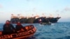 In this handout photo provided by the Philippine Coast Guard, members of the Philippine Coast Guard use rubber boats as they patrol beside Chinese vessels moored at Whitsun Reef, South China Sea, April 14, 2021.