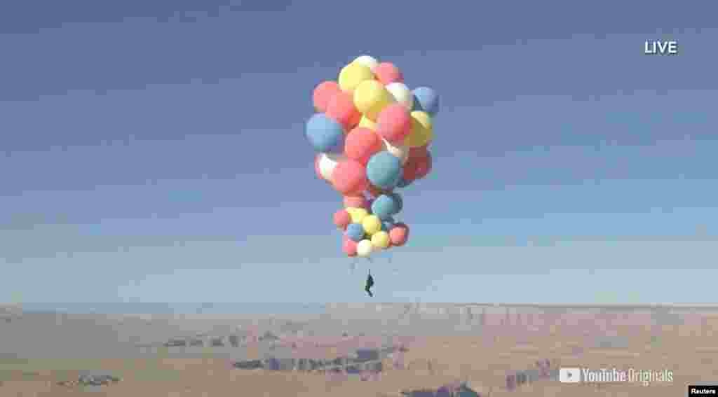 Extreme performer David Blaine hangs with a parachute under several balloons during a stunt to fly thousands of meters into the air, in this still image from video taken over Page, Arizona, Sept. 2, 2020. (David Blaine/Handout)