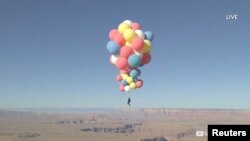 Extreme performer David Blaine hangs with a parachute under a cluster of balloons during a stunt to fly thousands of feet into the air in a still image from video taken over Page, Arizona, Sept. 2, 2020. (David Blaine/Handout)