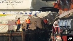 FILE—Staffers of port, left, stand on the aid platform and Open Arms aid group on the ship as it prepares to ferry some 200 tons of rice and flour directly to Gaza, at the port in Larnaca, Cyprus, on March 10, 2024.