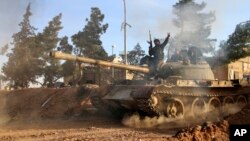 FILE - А volunteer fighter with Syrian government forces sits atop a tank in the province of Raqqa, Syria, Feb. 17, 2016. Backed by Russia and Iran, Syrian forces seen as much better positioned than the U.S.-led coalition and its regional allies to take 