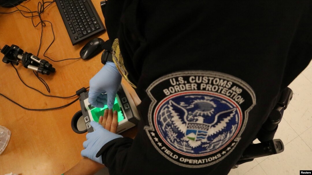 FILE - A woman who is seeking asylum has her fingerprints taken by a U.S. Customs and Border patrol officer at a pedestrian port of entry from Mexico to the United States, in McAllen, Texas, May 10, 2017.