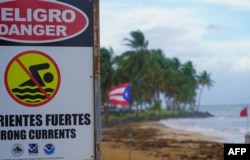 Tanda peringatan bertuliskan "Bahaya, Dilarang Berenang" di pantai Luquillo, Puerto Riko, 13 Agustus 2024, saat Badai Tropis Ernesto mendekat. (Jaydee Lee SERRANO / AFP)