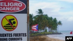 Un cartel de advertencia que dice "Peligro, no nadar" se ve en la playa de Luquillo, Puerto Rico, el 13 de agosto de 2024, mientras se acerca la tormenta tropical Ernesto.