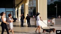 Tourists walk on the beach promenade as French police officers stand guard ahead of the upcoming G7 Summit in Biarritz, Aug. 22, 2019. 