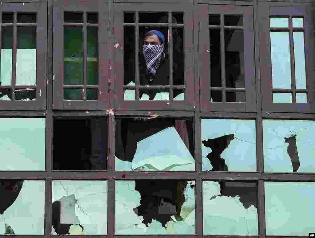 A Kashmiri man watches from a damaged house during a gun battle between government forces and suspected rebels on the outskirts of Srinagar, Indian-controlled Kashmir.