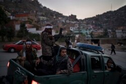 FILE - Taliban fighters sit on the back of a pickup truck as they stop on a hillside in Kabul, Afghanistan, Sept. 19, 2021.