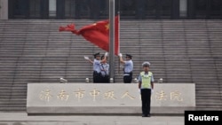 FILE - Policemen hoist a Chinese national flag at the entrance of a court in Jinan, where former disgraced politician Bo Xilai was held, September 22, 2013. 