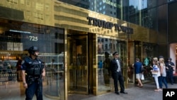 FILE - People pass police security an a building doorman in front of Trump Tower in New York.