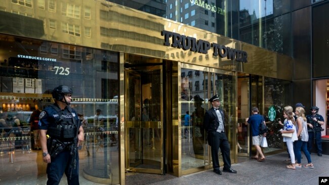 FILE - People pass police security an a building doorman in front of Trump Tower in New York.