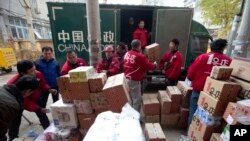 Delivery men for an online shopping portal sort through goods at a distribution center in Beijing Monday, Nov. 11, 2013. Nov. 11 also dubbed "Singles Day"