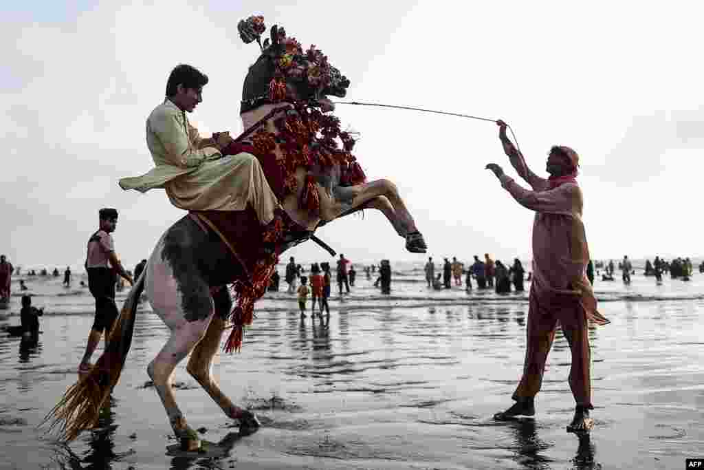 A youth enjoys a horse ride along a beach in Karachi, Pakistan.