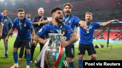 Italy's Lorenzo Insigne, holding a trophy, celebrates with teammates after they win the Euro 2020 soccer championship final match against England, at Wembley stadium, London, July 11, 2021.