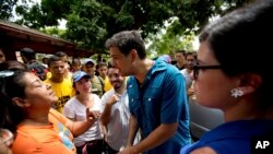 FILE - Opposition candidate Carlos Ocariz, who is running for governor of Miranda state, speaks with a woman as he campaigns in Guarenas, on the outskirts of Caracas, Venezuela, Oct. 7, 2017. 