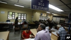 An Indian woman, foreground left, waits to send a telegram at Bharat Sanchar Nigam Limited (BSNL), a state-run telecom company in Bangalore, India, June 14, 2013.