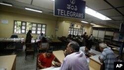 An Indian woman, foreground left, waits to send a telegram at Bharat Sanchar Nigam Limited (BSNL), a state-run telecom company in Bangalore, India, June 14, 2013.