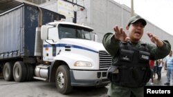 A Venezuelan National Guard walks in front of a truck as it leaves the facility used by Empresas Polar as a distribution center, while company employees shout inside, during the occupation of its installations by government representatives in Caracas, July 30, 2015.