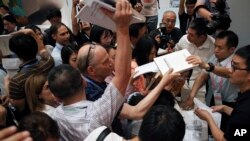 Reporters scramble to get copies of the China's national defense white paper before a press conference at the State Council Information Office in Beijing, July 24, 2019. 