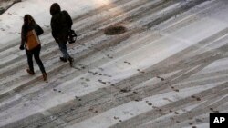 FILE - Pedestrians leave footprints in the snow as they cross a street in downtown Kansas City, Missouri, Dec. 17, 2016. A new winter storm featuring freezing rain is expected to hit the nation's mid-section Friday, Dec. 13, 2017.