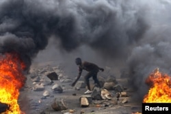 FILE - A protester sets up a barricade during a protest against Burundi President Pierre Nkurunziza and his bid for a third term in Bujumbura, Burundi, May 22, 2015.
