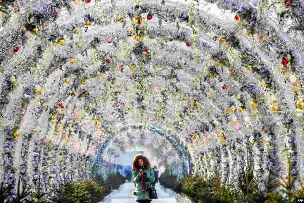 A woman walks in the tunnel decorated with festive lights for the upcoming holidays in central Moscow, Russia.