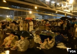 佔領中環行動進行期間下起傾盆大雨，無阻示威群眾，手持雨傘坐在馬路上繼續表達訴求。（美國之音湯惠芸攝）