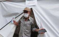 Erri Suprijadi berusia 70 tahun meninggalkan tenda setelah menerima suntikan vaksin COVID-19 di sebuah puskesmas di Jakarta, 8 Februari 2021. (Foto: Achmad Ibrahim/AP)