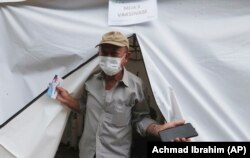 Erri Suprijadi berusia 70 tahun meninggalkan tenda setelah menerima suntikan vaksin COVID-19 di sebuah puskesmas di Jakarta, 8 Februari 2021. (Foto: Achmad Ibrahim/AP)