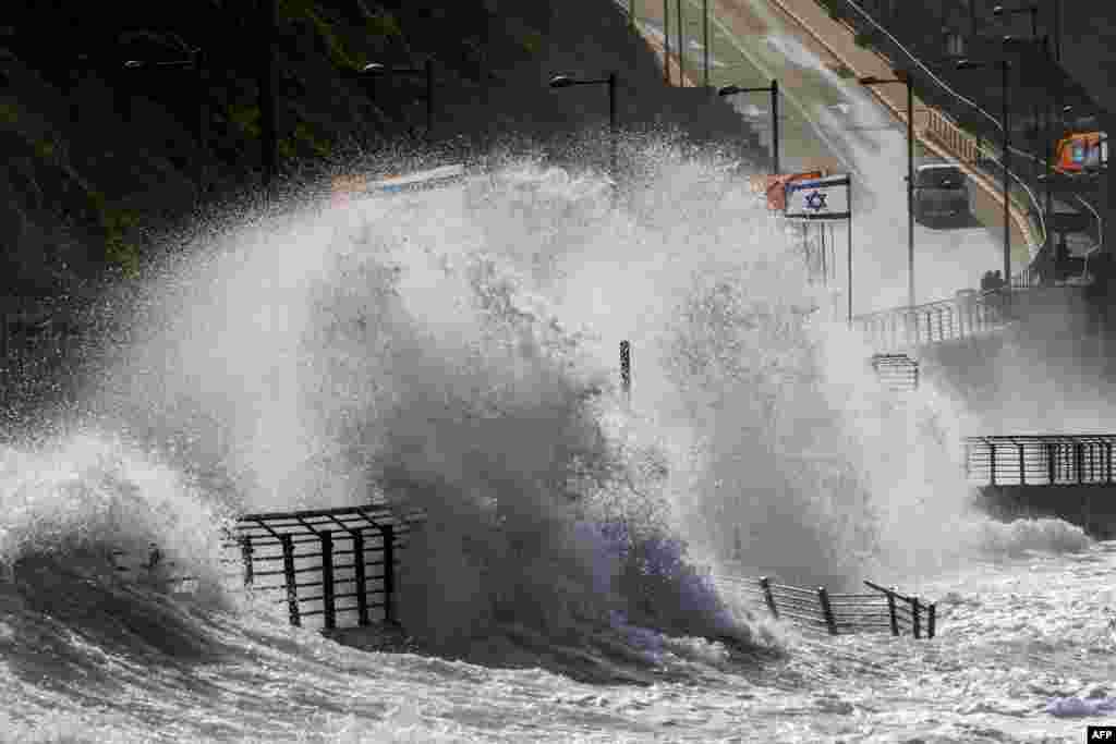 A picture taken on January 19, 2018 shows waves beating against a highway during a winter storm as Israeli flags flutter in the Mediterranean coastal town of Netanya, north of Tel Aviv.