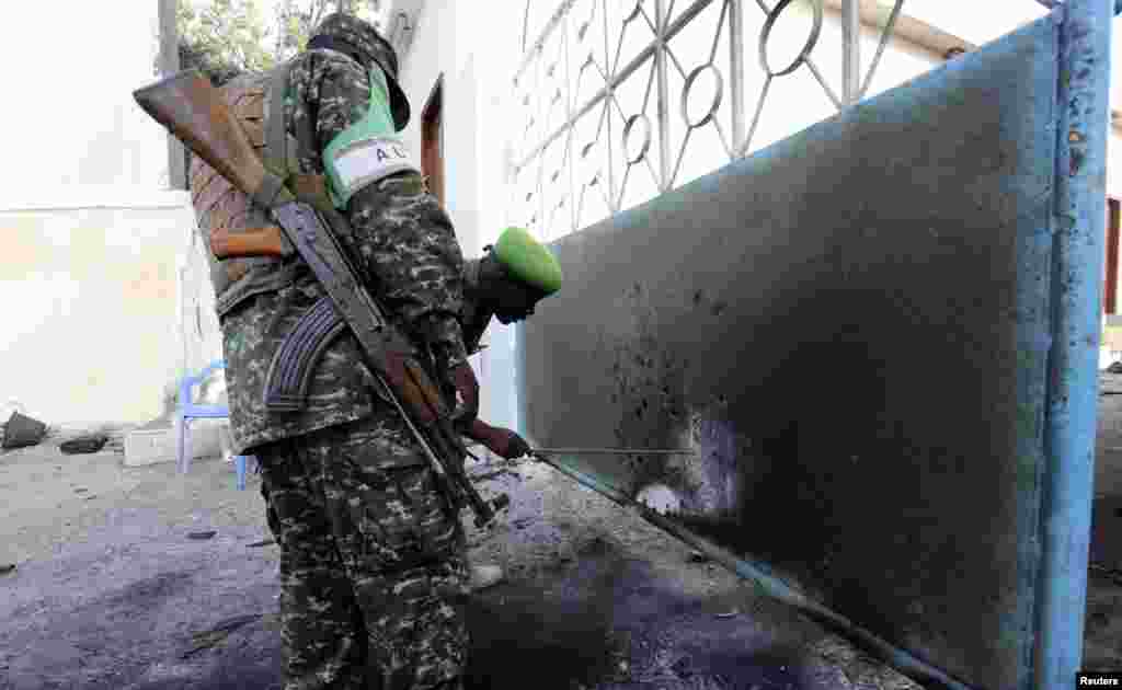 Soldiers serving in the African Union Mission in Somalia (AMISOM) assess the damage sustained during an attack at the presidential palace in Mogadishu, July 9, 2014.