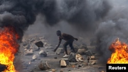 ፋይል ፎቶ - FILE - A protester sets up a barricade during a protest against Burundi President Pierre Nkurunziza and his bid for a third term in Bujumbura, Burundi, May 22, 2015. 