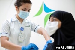 FILE PHOTO: A medical worker injects a dose of a vaccine against the coronavirus disease (COVID-19) to a woman, in Dubai, United Arab Emirates, Dec. 23, 2020.