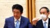 Perdana Menteri Jepang Shinzo Abe, kiri, memberi isyarat saat Kepala Sekretaris Kabinet Yoshihide Suga melihat pada akhir konferensi pers di kantor Abe di Tokyo pada hari Senin, 4 Mei 2020. (Foto: AP)