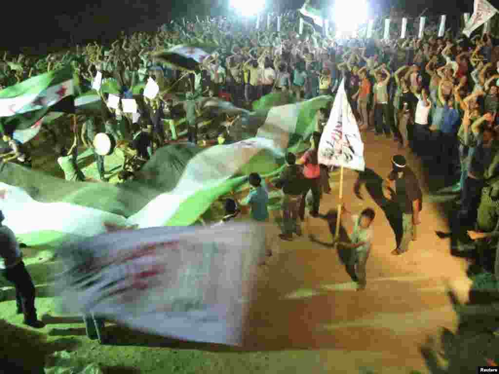 Demonstrators hold opposition flags during a protest against Syria's President Bashar al-Assad in Kfr Suseh, Damascus, Syria. June 18, 2012