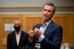 FILE - California Governor Gavin Newsom, right, speaks during a tour of a cooling center in Sacramento, California, Aug. 18, 2020. Newsom declared an emergency Tuesday over wildfires burning throughout the state.