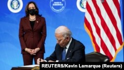 美国总统拜登签署一项行政命令后谈他的政府加强美国制造业的计划，副总统哈里斯站在一旁。(2021年1月25日)
