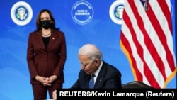 U.S. President Joe Biden signs an executive order after speaking about his administration's plans to strengthen American manufacturing as Vice President Kamala Harris listens in the South Court Auditorium at the White House in Washington, U.S., January 25, 2021. REUTERS/Kevin Lam