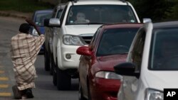 FILE - A homeless man begs for alms at a busy intersection in Johannesburg, Wednesday, Feb. 24, 2021