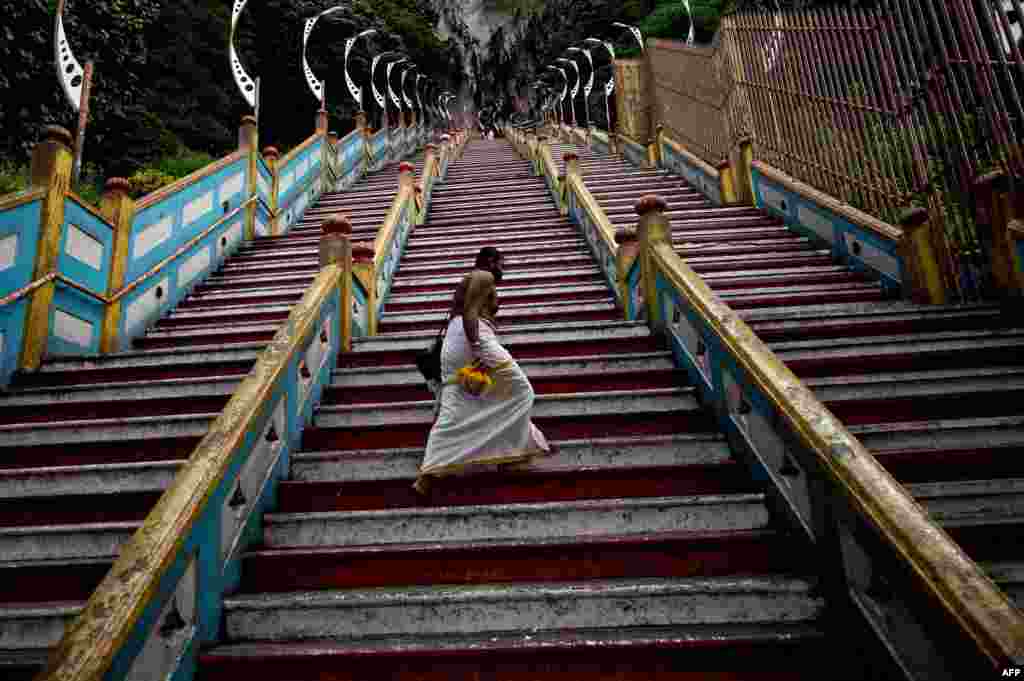 A Hindu priest walks up the 272 stairs to the Batu Caves temple outside of Kuala Lumpur, Malaysia. The temple built inside the centuries-old, limestone-formed Caves is one of the most popular Hindu shrines outside India and is dedicated to Lord Murugan.