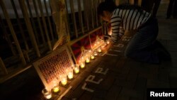 A protester arranges candles during a candlelight vigil outside a China Liaison Office in Hong Kong, February 13, 2013.
