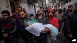 Mohammad Shouman menggendong jenazah putrinya, Masa, yang tewas dalam serangan udara Israel di Jalur Gaza, saat pemakamannya di Rafah, Gaza selatan, 17 Januari 2024. (Foto: AP)