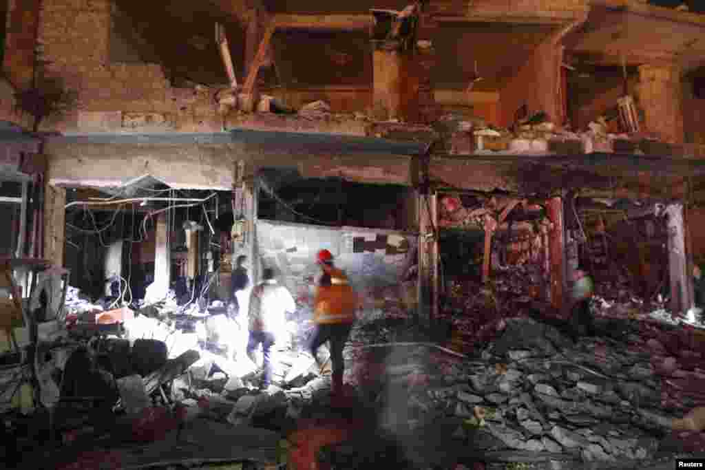 Civilians and rescuers search under rubble at a site hit by what activists say was a Scud missile from forces loyal to Syria's President Bashar al-Assad in Raqqa, Nov. 28, 2013. 